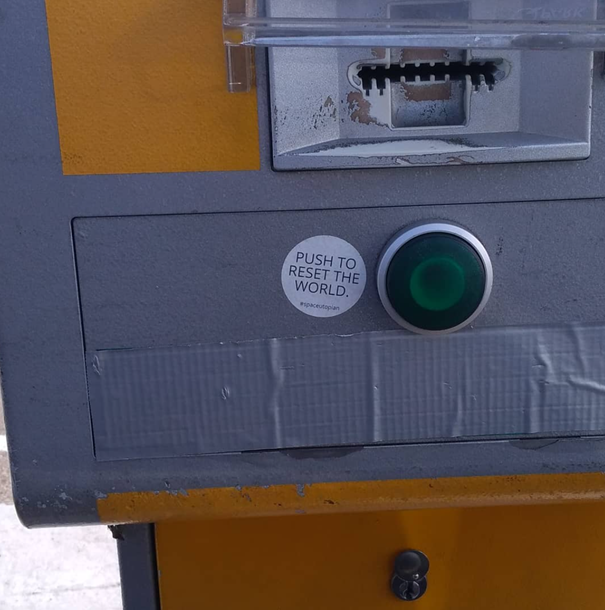 Push to reset the world, sticker art on a ticket dispenser (Charleroi, BE).