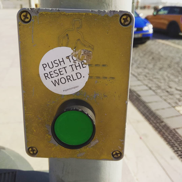 Push to reset the world, sticker art at a pedestrian crossing in Lisbon (Lisbon, PT).
