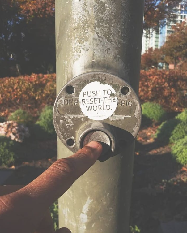 Push to reset the world, sticker art at a pedestrian crossing (NYC, USA).