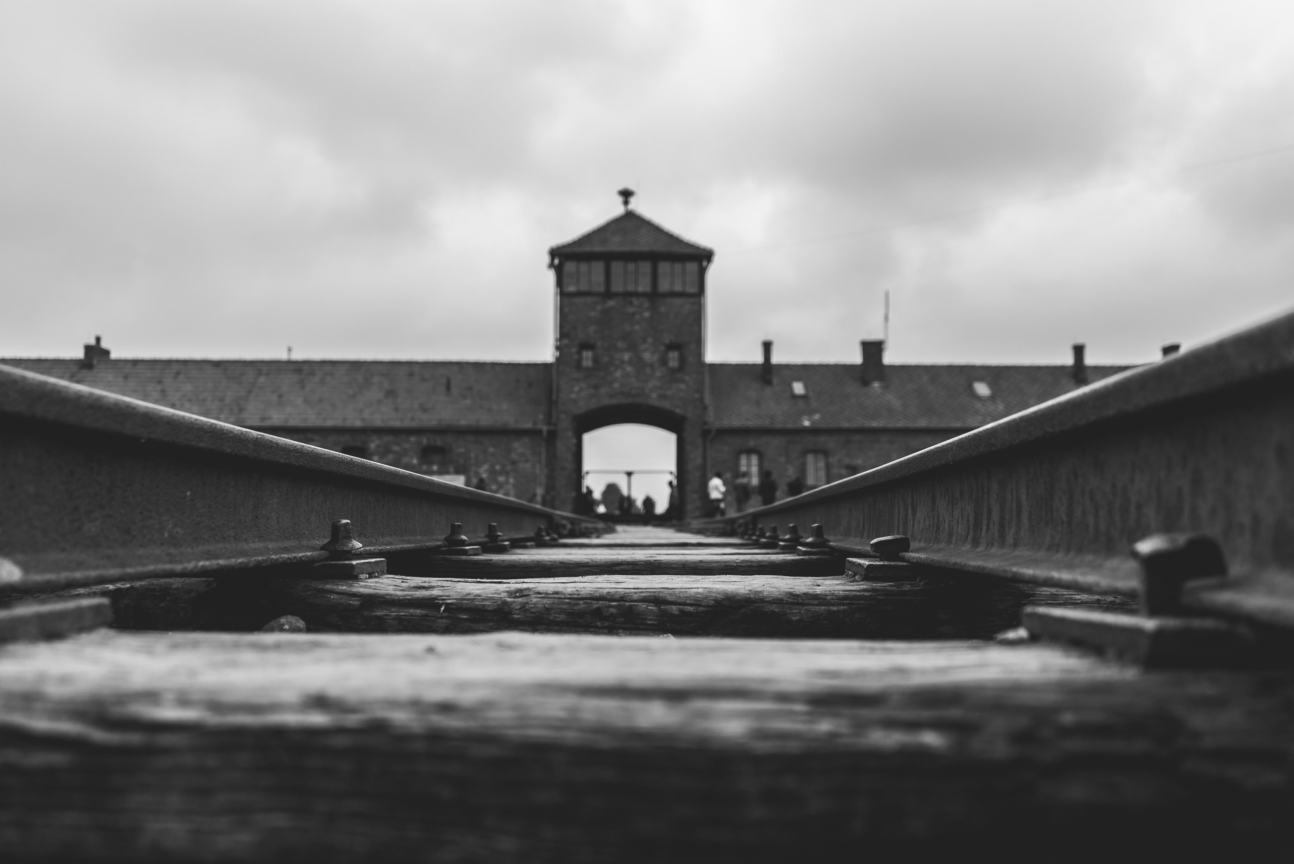 A powerful black and white photo showcasing the railway leading to the entrance of a concentration camp.